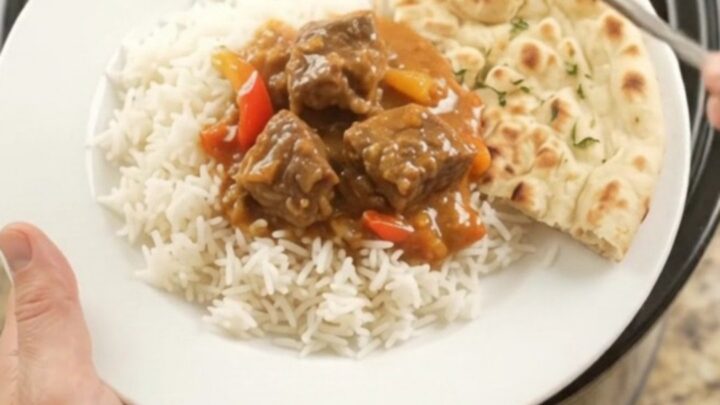 A bowl of creamy red curry beef brisket with tender beef cubes and bell pepper slices, garnished with fresh cilantro.