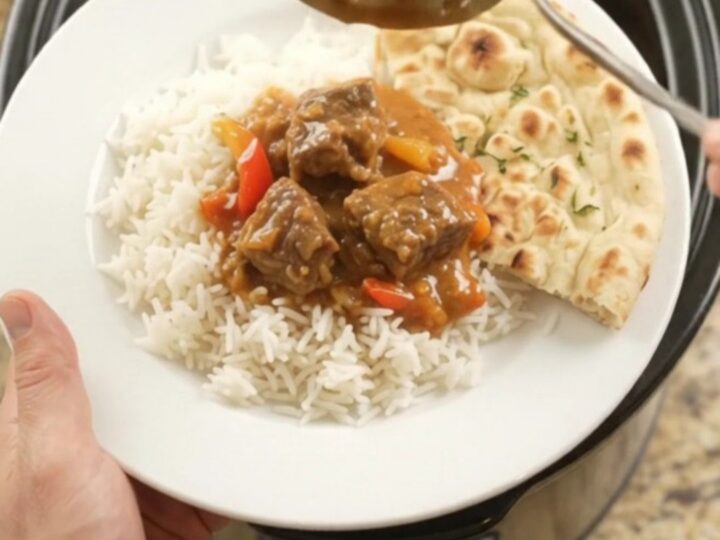 A bowl of creamy red curry beef brisket with tender beef cubes and bell pepper slices, garnished with fresh cilantro.
