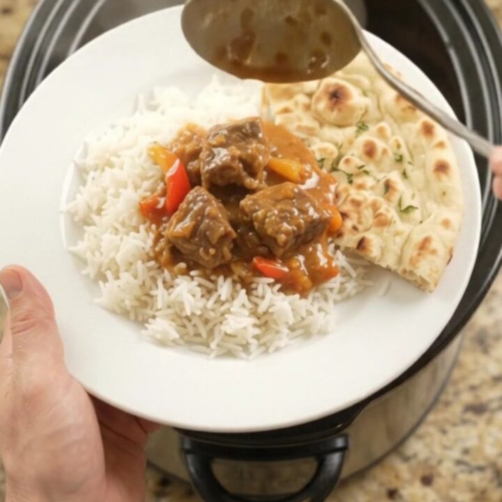 A bowl of creamy red curry beef brisket with tender beef cubes and bell pepper slices, garnished with fresh cilantro.