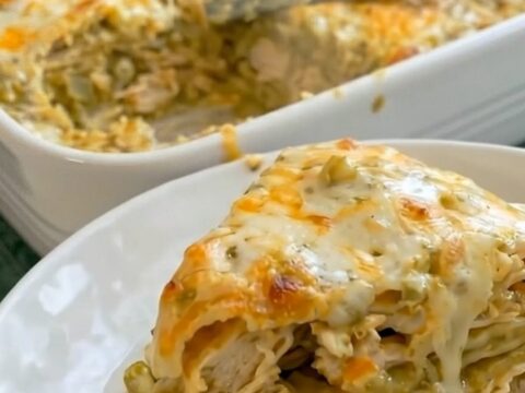 A delicious slice of cheesy green chili chicken enchilada casserole served on a white plate
