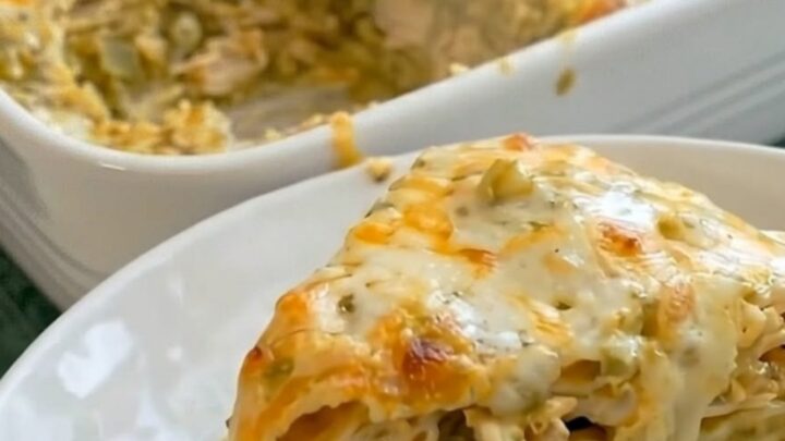 A delicious slice of cheesy green chili chicken enchilada casserole served on a white plate