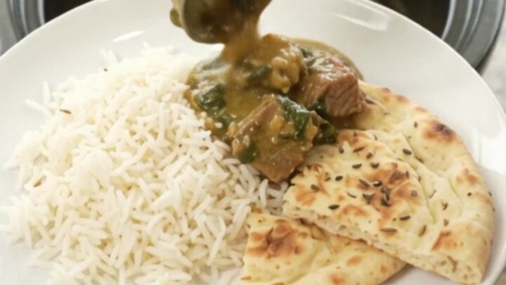 Slow cooker creamy spinach saag beef brisket in a black crock, with steam rising