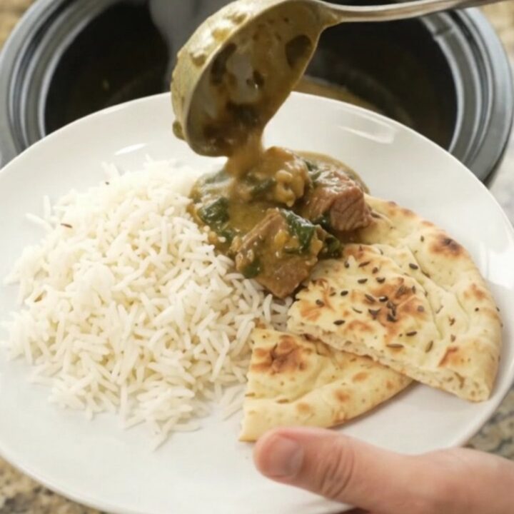 Slow cooker creamy spinach saag beef brisket in a black crock, with steam rising