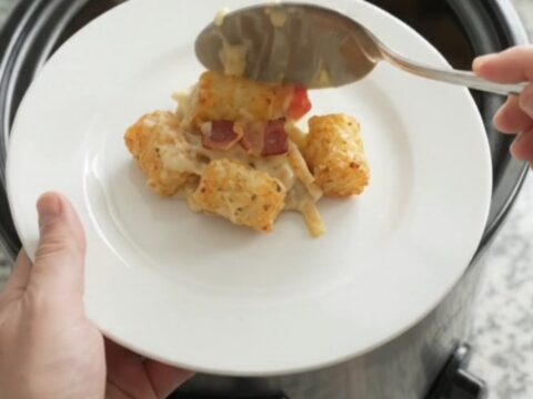 Bubbling tater tot casserole in a slow cooker with melted cheese and crispy onions