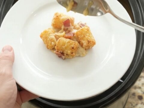 Golden tater tots and melted smoked Gouda in a slow cooker, with bacon and onions visible