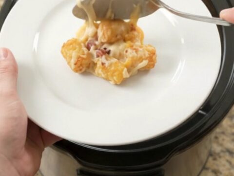 Bubbling tater tot bake in a slow cooker with melted cheese and bacon.