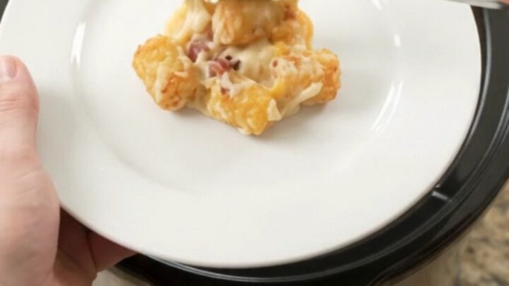 Bubbling tater tot bake in a slow cooker with melted cheese and bacon.