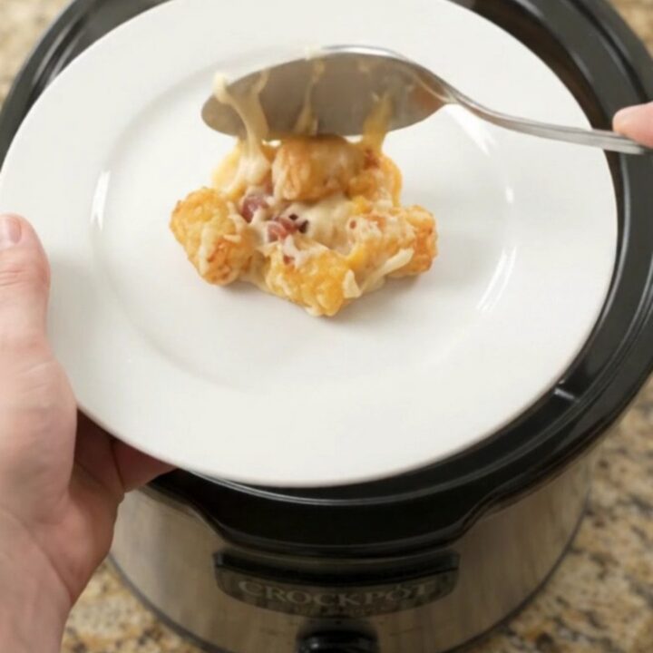 Bubbling tater tot bake in a slow cooker with melted cheese and bacon.