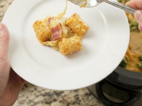 A bubbling slow cooker filled with golden tater tots, broccoli, and melted cheddar cheese.