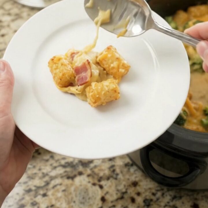 A bubbling slow cooker filled with golden tater tots, broccoli, and melted cheddar cheese.