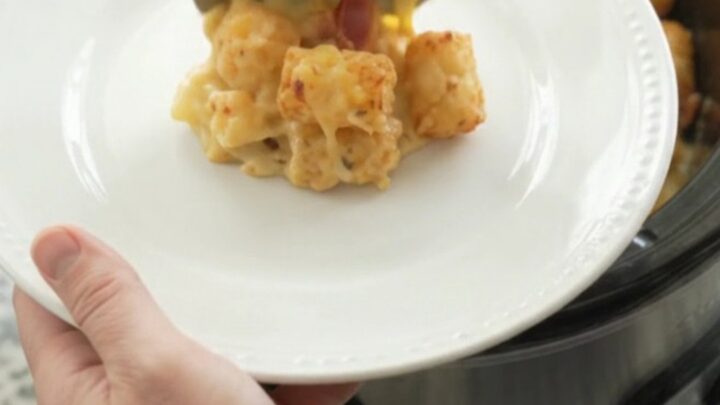 Bubbling smoked gouda broccoli tater tot bake in a black crockpot, with melted cheese and steam rising.