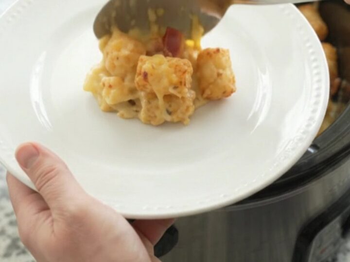 Bubbling smoked gouda broccoli tater tot bake in a black crockpot, with melted cheese and steam rising.