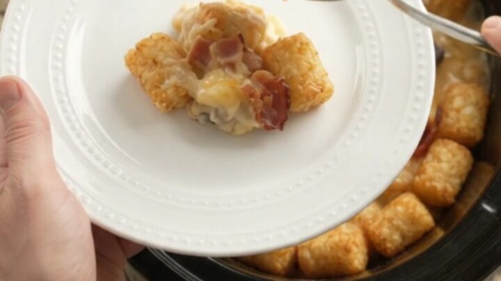 Bubbling slow cooker tater tot bake with melted smoked gouda and Parmesan, garnished with fresh herbs.