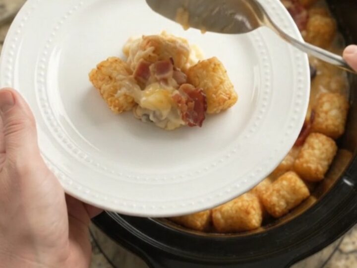 Bubbling slow cooker tater tot bake with melted smoked gouda and Parmesan, garnished with fresh herbs.