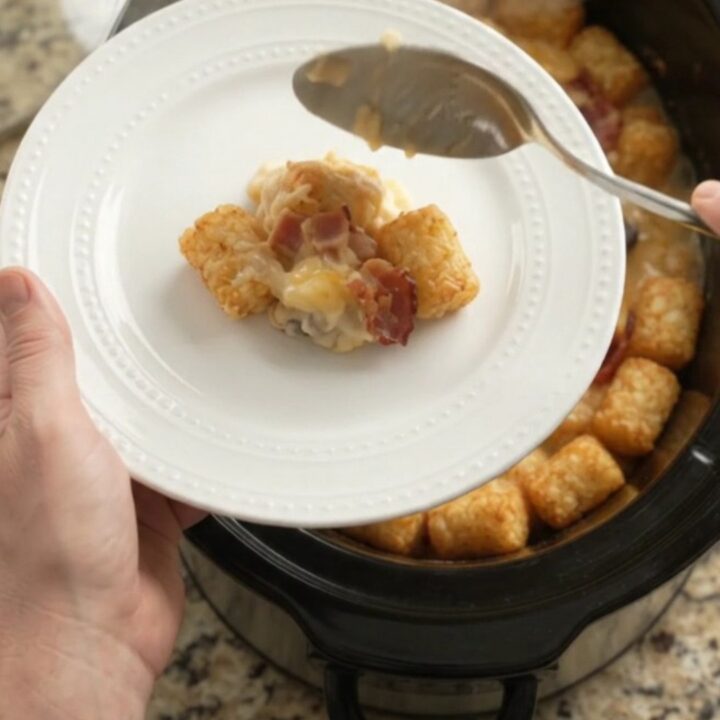 Bubbling slow cooker tater tot bake with melted smoked gouda and Parmesan, garnished with fresh herbs.