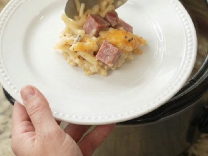 Slow cooker full of golden cheesy hashbrown casserole with melted smoked gouda and parmesan.