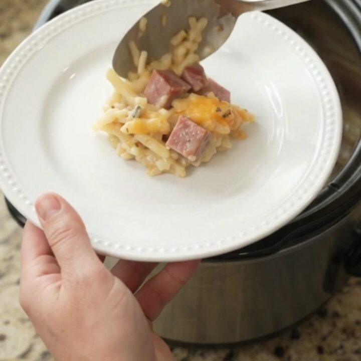 Slow cooker full of golden cheesy hashbrown casserole with melted smoked gouda and parmesan.