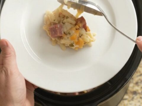 Slow-cooker hashbrown bake with melted pepper jack and crispy onions, served in a black Crockpot.