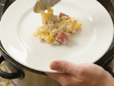 Bubbling cheesy hashbrown bake in a slow cooker with melted Colby-Jack and ham cubes.