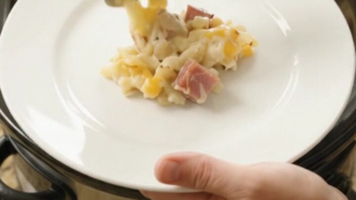 Bubbling cheesy hashbrown bake in a slow cooker with melted Colby-Jack and ham cubes.