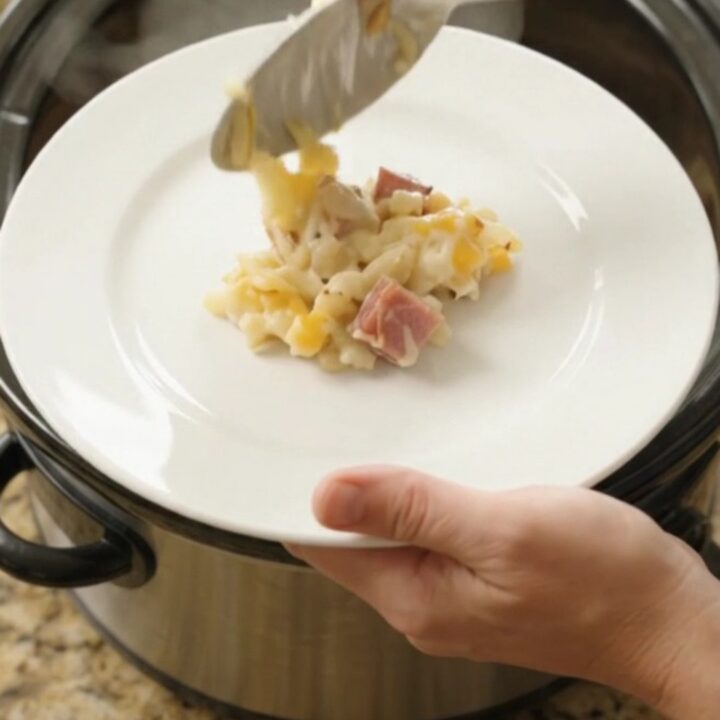 Bubbling cheesy hashbrown bake in a slow cooker with melted Colby-Jack and ham cubes.