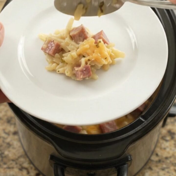 A bubbling slow cooker filled with cheesy hashbrown casserole, topped with melted smoked Gouda and Parmesan