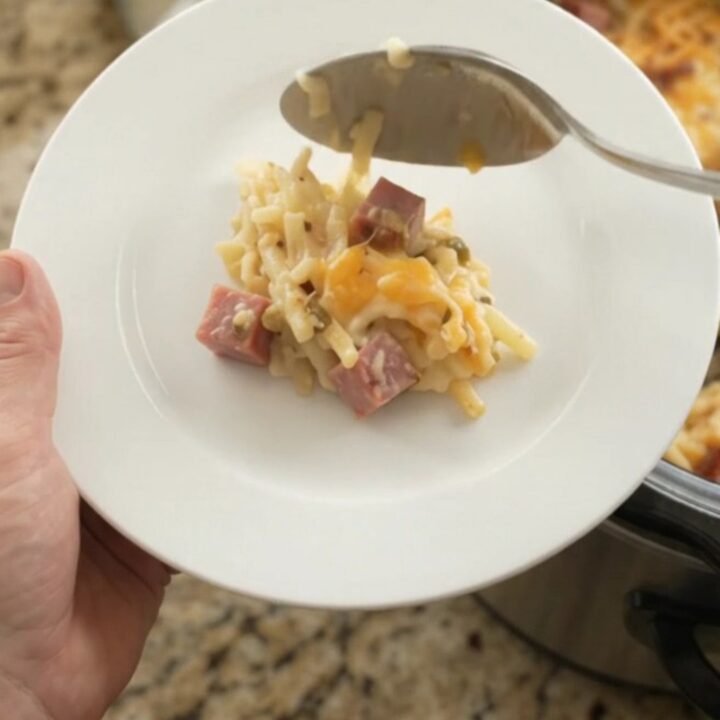 Slow cooker filled with bubbling hashbrown casserole topped with melted pepper jack and crispy onions