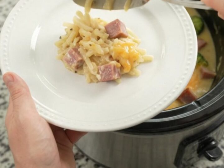 Slow cooker filled with bubbling smoked Gouda broccoli hashbrown casserole, steam rising