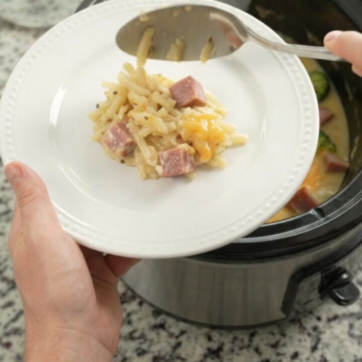 Slow cooker filled with bubbling smoked Gouda broccoli hashbrown casserole, steam rising