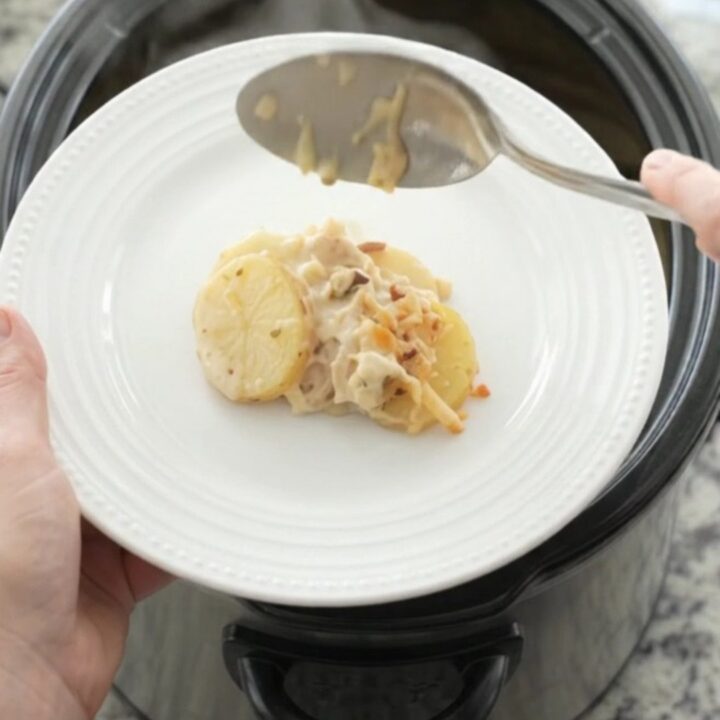 Slow cooker filled with creamy pepper jack scalloped potatoes, topped with crispy onions