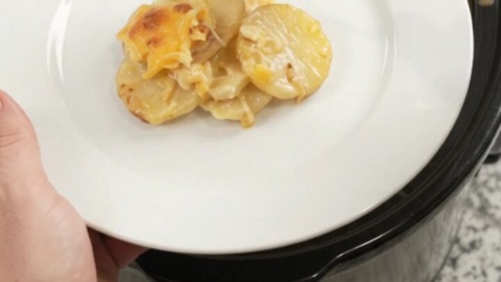 Crockpot cheddar roasted garlic scalloped potatoes bubbling in a slow cooker