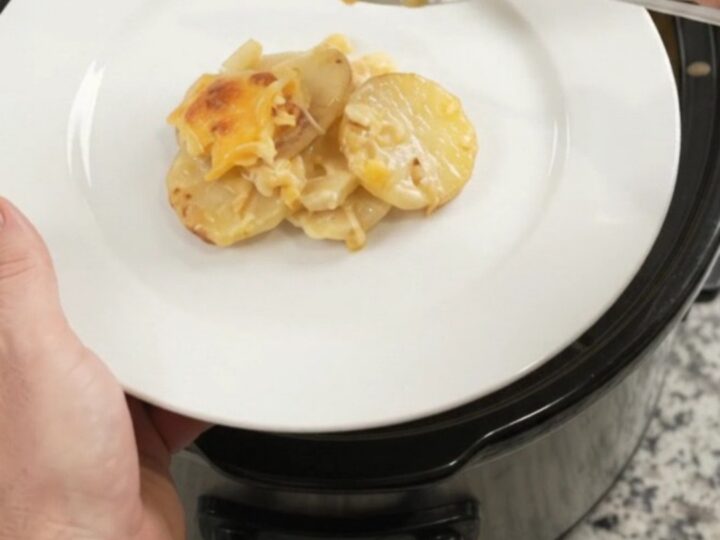 Crockpot cheddar roasted garlic scalloped potatoes bubbling in a slow cooker