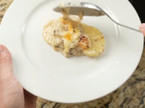 Creamy slow-cooker scalloped potatoes with melted cheese and crispy onions in a black crockpot