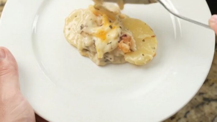 Creamy slow-cooker scalloped potatoes with melted cheese and crispy onions in a black crockpot
