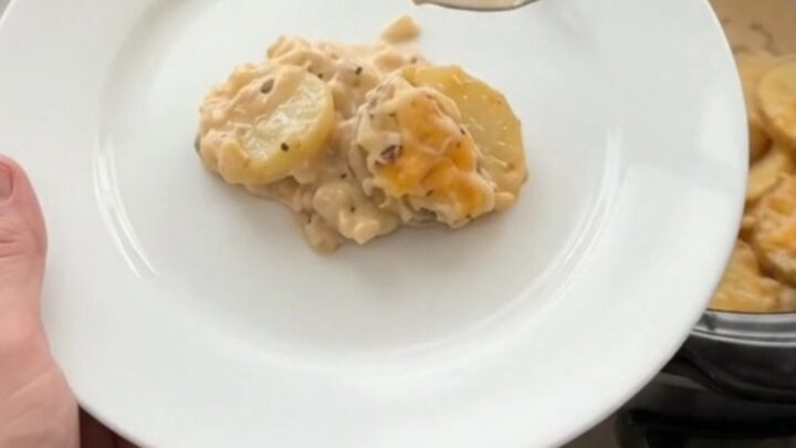 A slow cooker filled with creamy smoked gouda scalloped potatoes, topped with melted cheese and steam rising.