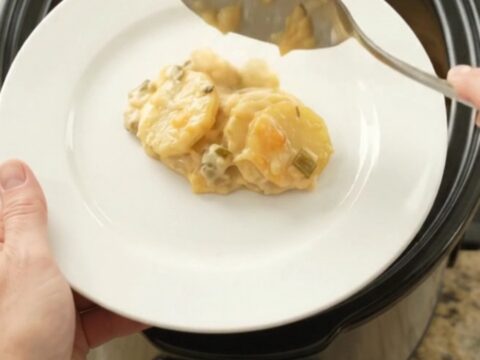 Slow cooker filled with bubbling scalloped potatoes topped with melted smoked Gouda and Parmesan.