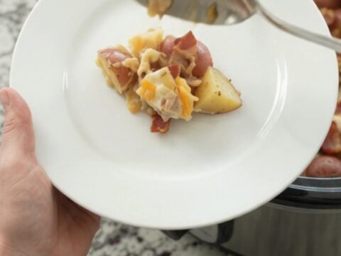 Slow cooker red potato bake with bacon, pepper jack, and crispy onions in a black Crockpot.