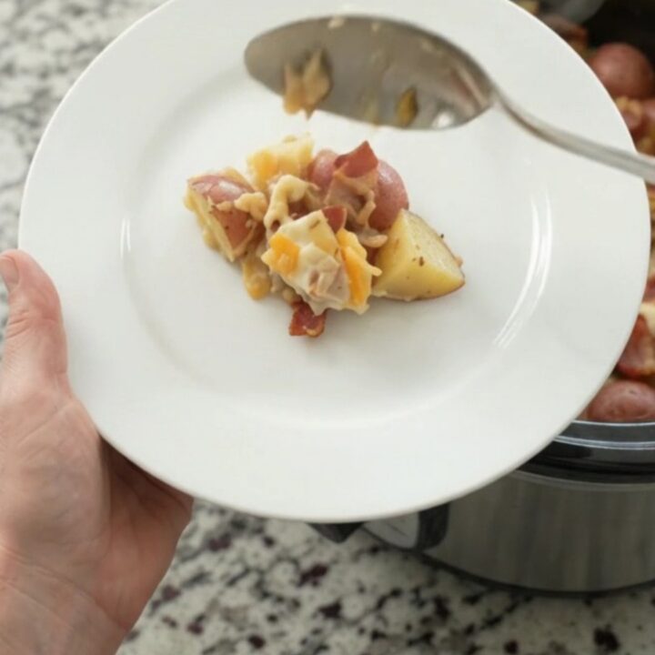 Slow cooker red potato bake with bacon, pepper jack, and crispy onions in a black Crockpot.