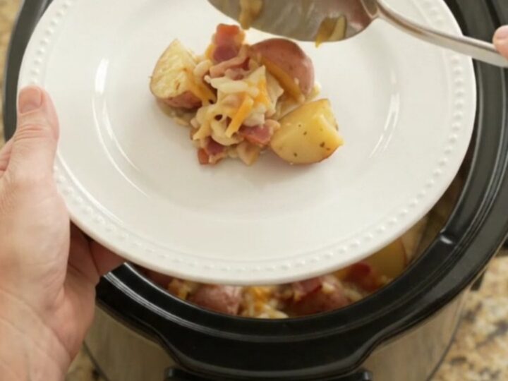 Slow cooker filled with bubbling cheesy potato bake with melted Colby-Jack and cream cheese