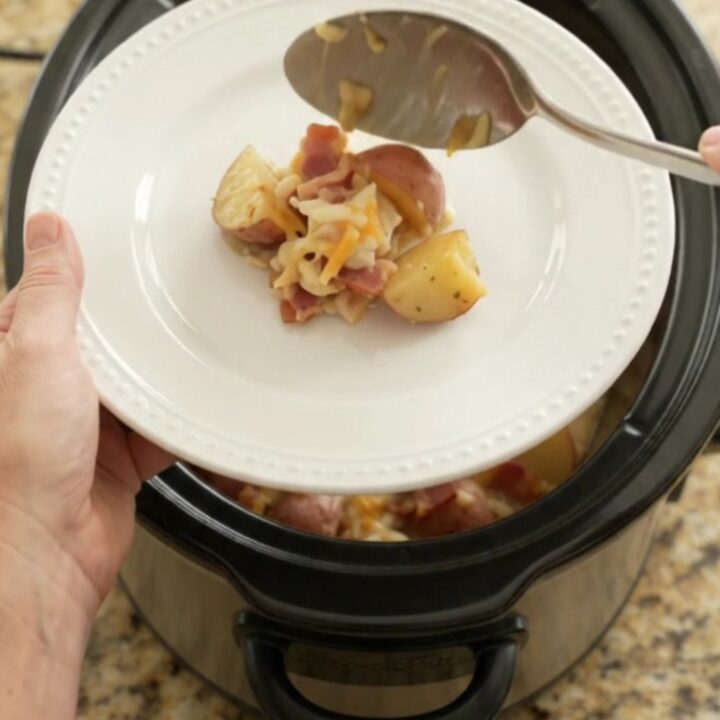 Slow cooker filled with bubbling cheesy potato bake with melted Colby-Jack and cream cheese