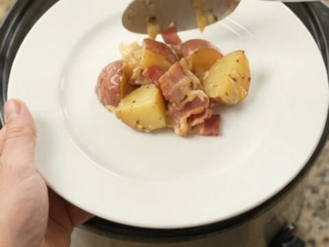 Slow cooker filled with bubbling potato bake topped with melted smoked Gouda and Parmesan