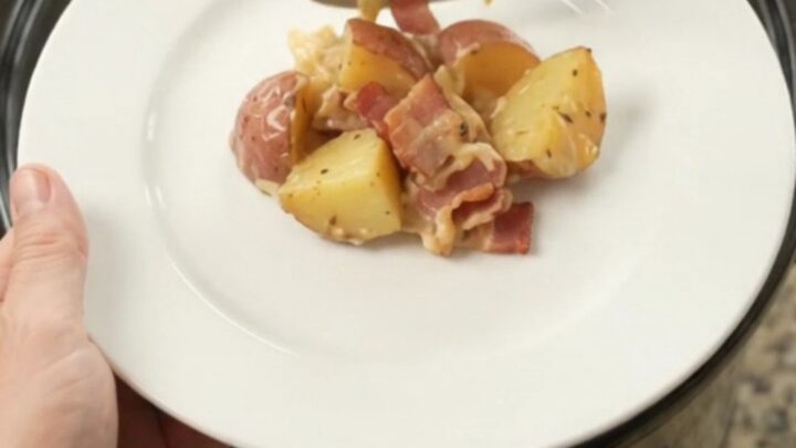 Slow cooker filled with bubbling potato bake topped with melted smoked Gouda and Parmesan