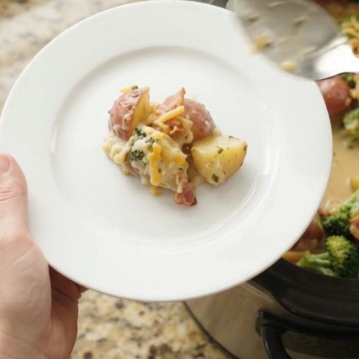 A slow cooker filled with creamy potato, bacon, and broccoli bake topped with melted pepper jack cheese and crispy onions.