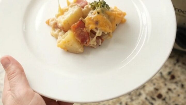 A slow cooker filled with creamy cheddar broccoli potato casserole, topped with melted cheese and steam rising.