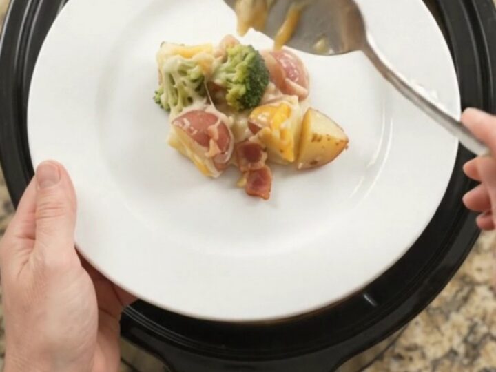 Slow cooker filled with creamy potato bake topped with melted Colby-Jack cheese and broccoli.