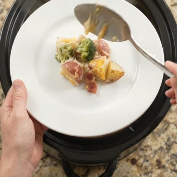 Slow cooker filled with creamy potato bake topped with melted Colby-Jack cheese and broccoli.