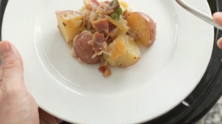 Slow cooker filled with creamy smoked gouda potato and broccoli bake, topped with melted cheese.