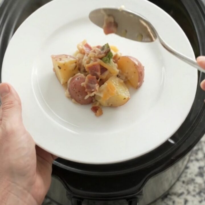 Slow cooker filled with creamy smoked gouda potato and broccoli bake, topped with melted cheese.