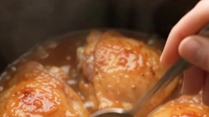 Glazed honey garlic chicken thighs in a slow cooker, coated in a shiny sauce