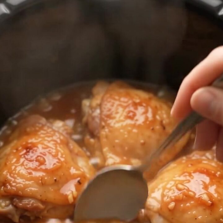 Glazed honey garlic chicken thighs in a slow cooker, coated in a shiny sauce
